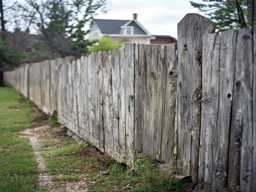Leaning wood fence section that has shifted out of line