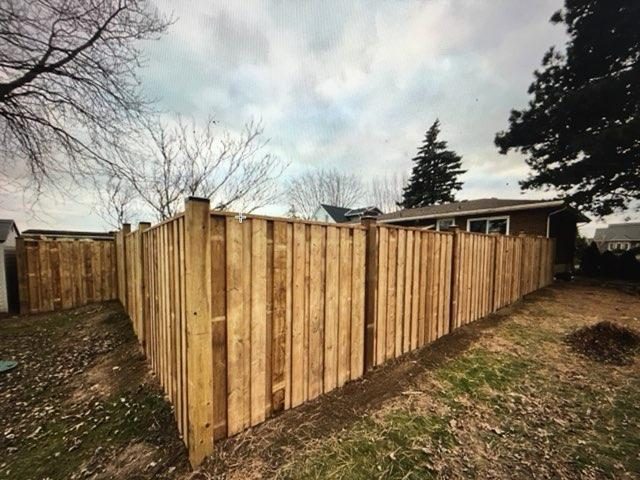 A new wood board fence built along the property line between two Ontario backyards