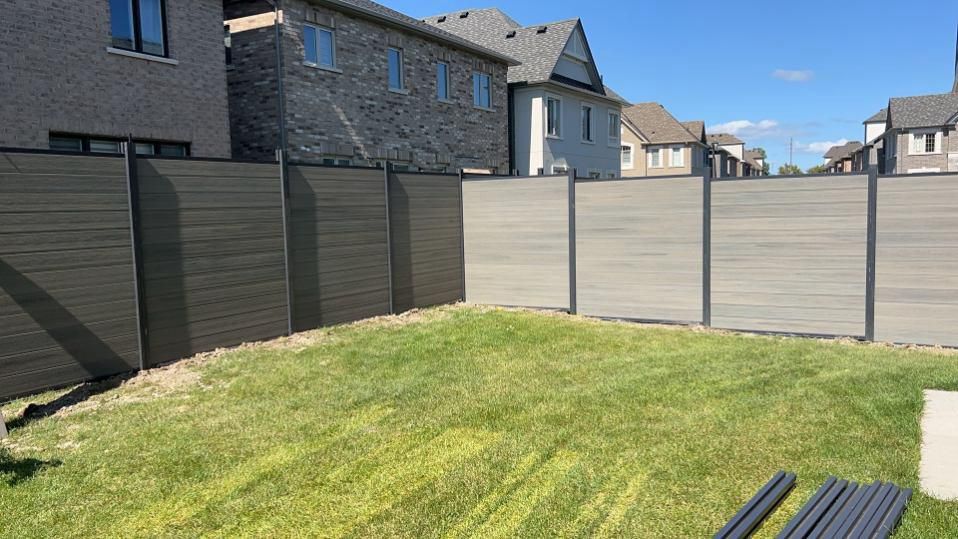 Grey composite fence along a new backyard lawn